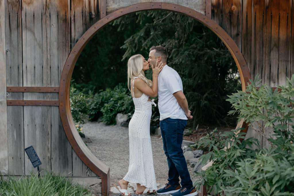 couple kissing while standing between garden feature at Botanic Gardens, top Denver photoshoot locations