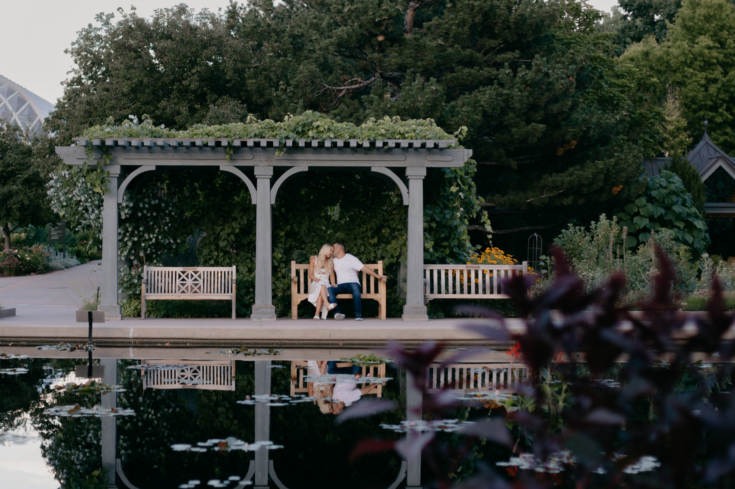 couple sitting on bench in front of pond at botanic gardens