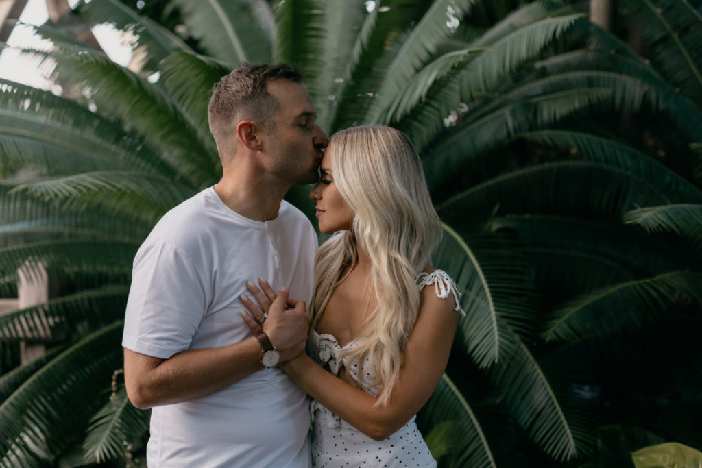 couple kissing standing in front of a palm tree in Denver Botanic Gardens engagement photos