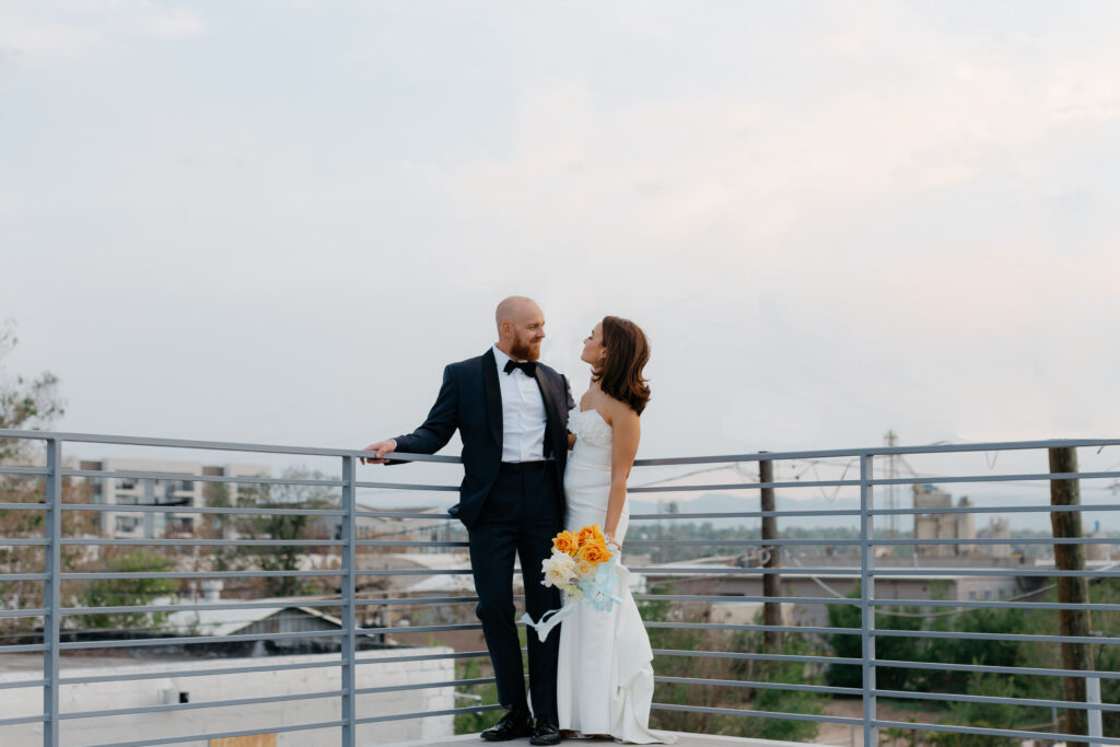bride and groom standing on rooftop patio of denver wedding venue