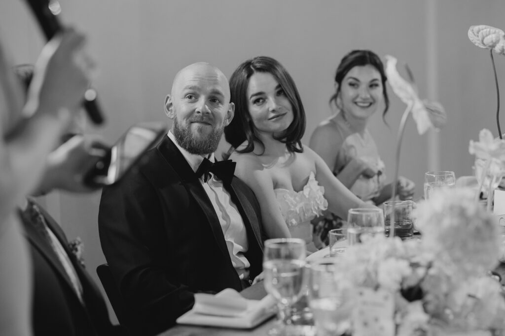 bride and groom smiling during toasts of wedding reception
