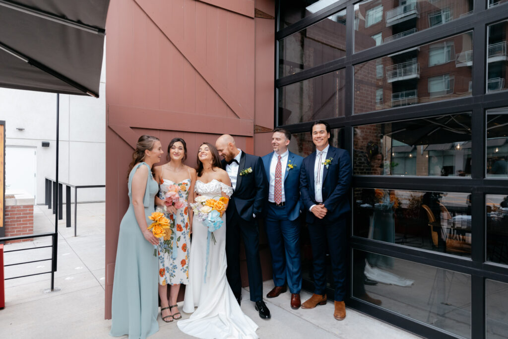 wedding party standing in front of large, industrial doors posing for photo