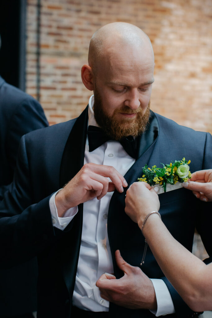 groom getting floral boutonniere on tux jacket