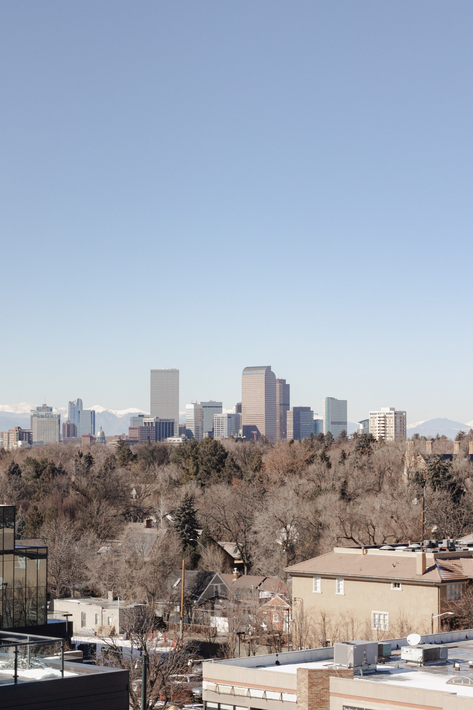 Skyline of Denver, Colorado city with Rocky Mountains in backdrop from Denver Halcyon Hotel