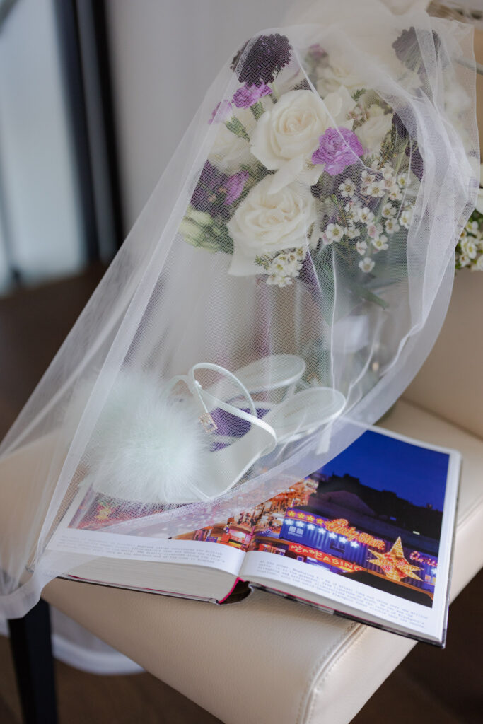 Designer shoes on art book, with wedding florals and veil covering at Denver Halcyon Hotel