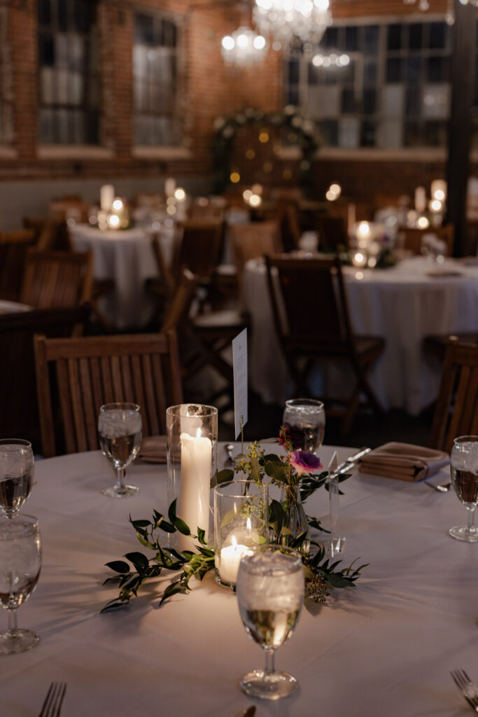 Candle lit table with purple florals and greenery on table during Denver wedding at Moss