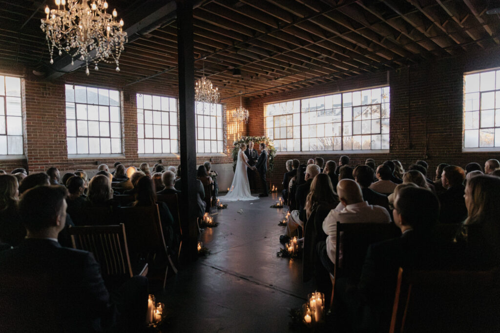 Wide view of Moss, Denver photos of wedding venue with industrial windows, brick walls, and chandeliers hanging from ceilings during Denver wedding