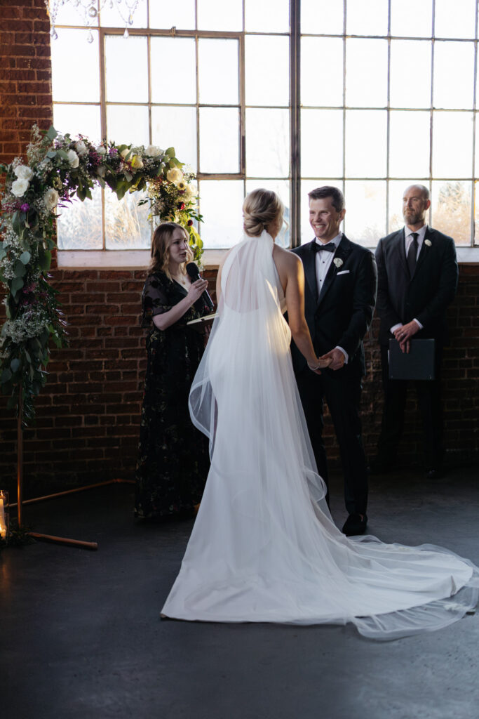 Bride and groom standing in front of modern, floral arch during Denver wedding inside Moss venue