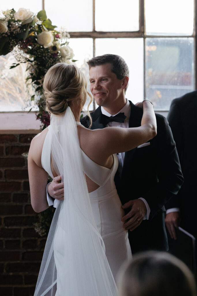 Groom embracing bride during Denver wedding ceremony at Moss venue