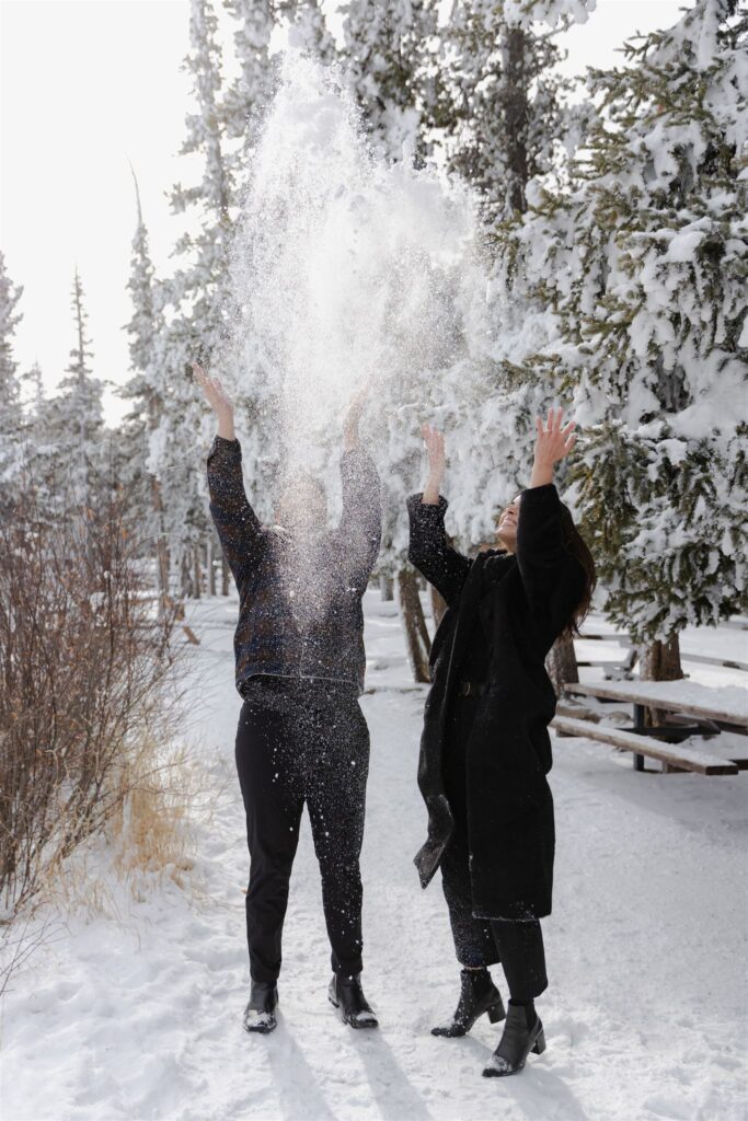Couple throwing snow in air during Colorado engagement photos