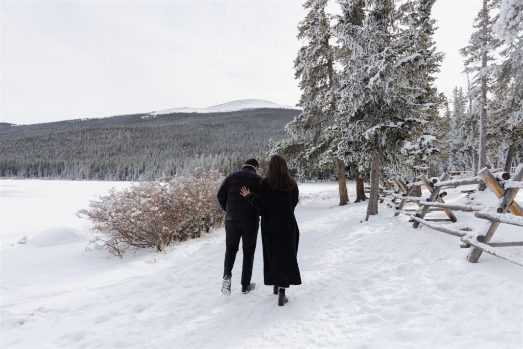 Couple walking towards snow covered trees around Colorado Lake