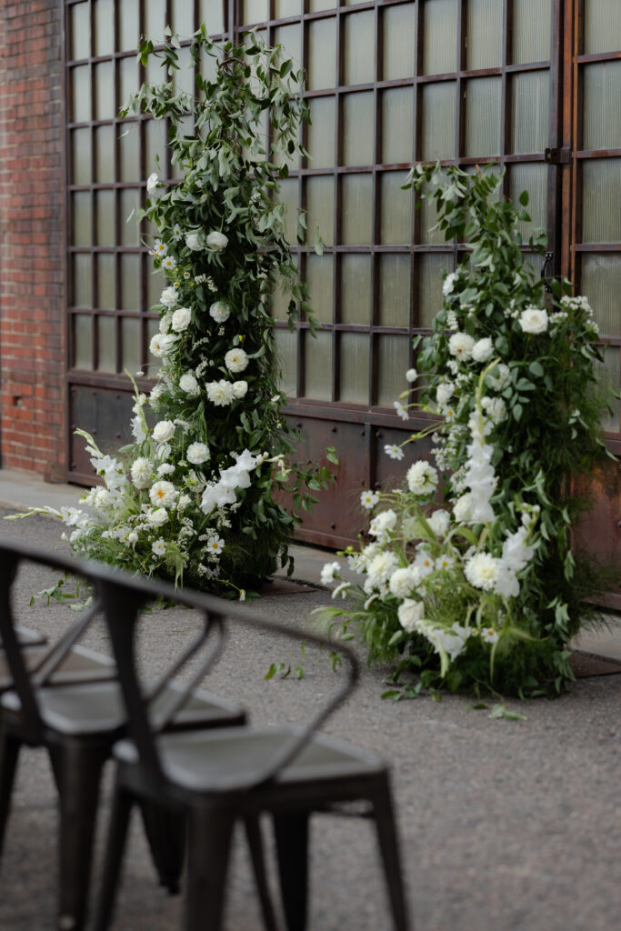 Best Denver Wedding Venues - White floral arch sitting in front of industrial windows