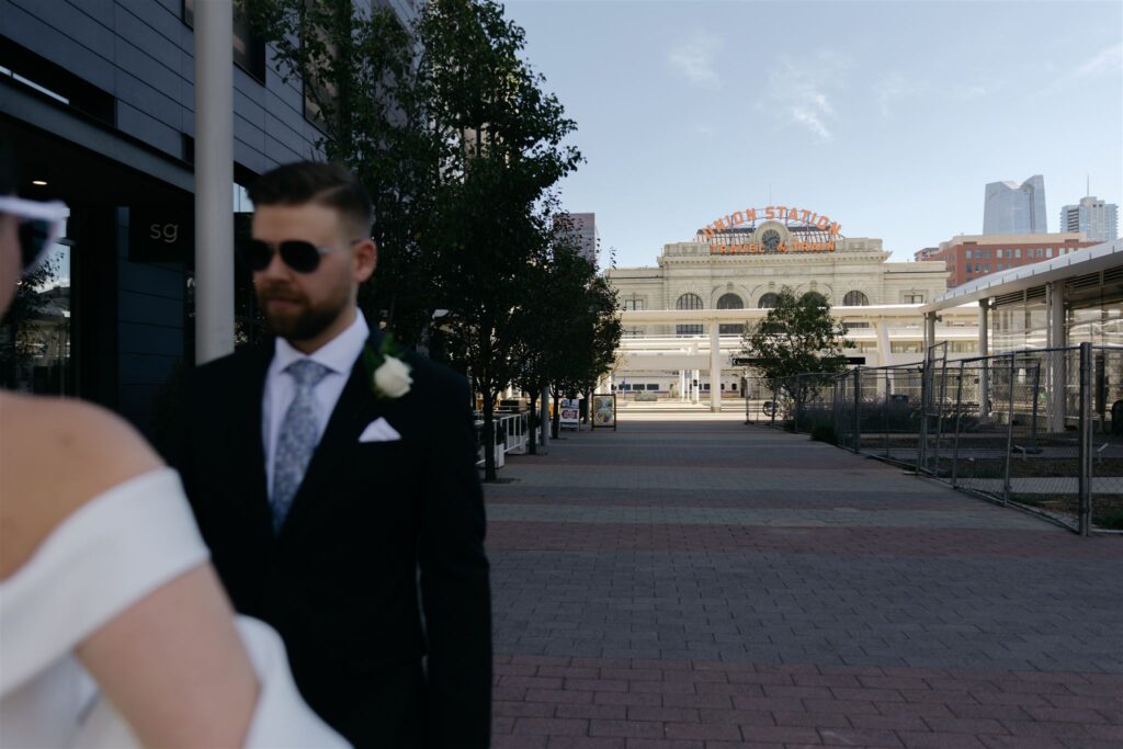 Bride and groom in conversation and off to the side with Denver Union Station in background and in focus