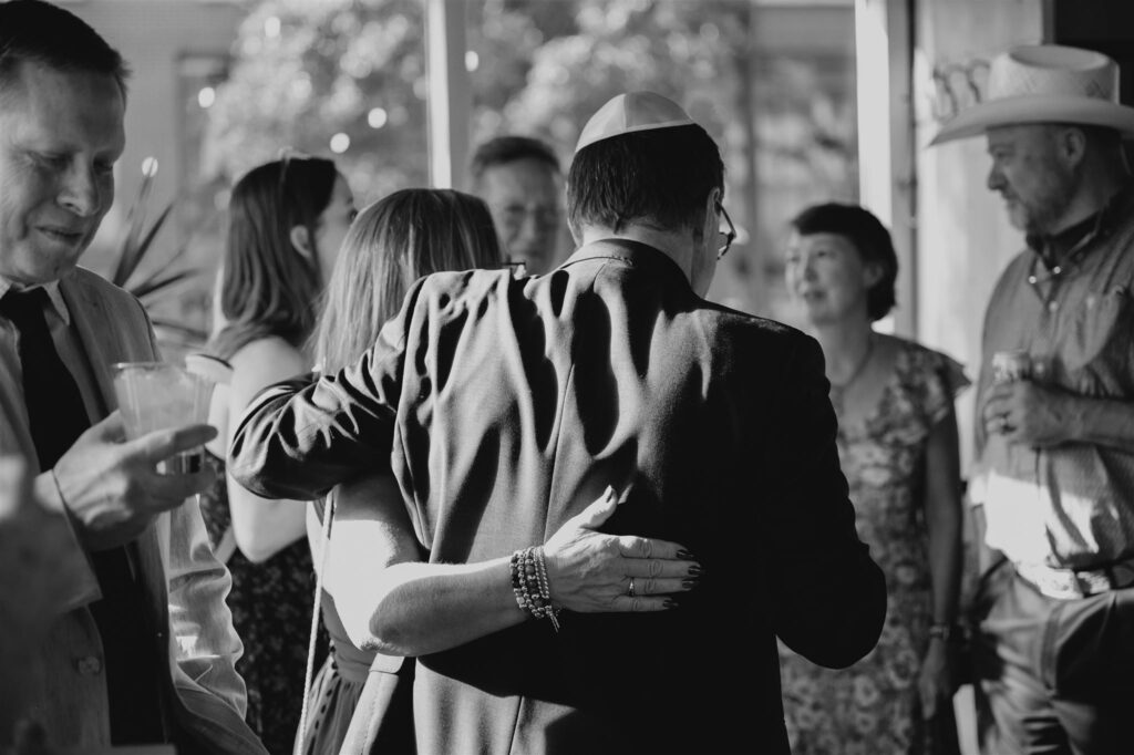 black and white image of a man giving a woman a hug, their backs to the cameras