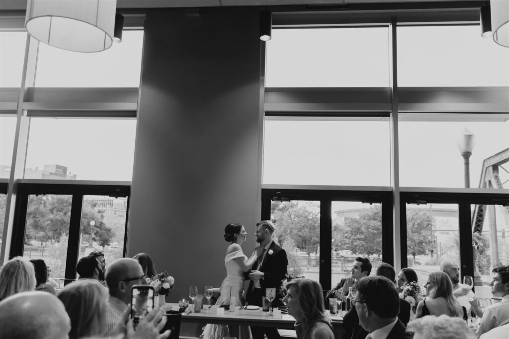 bride and groom standing up facing each other in private dining room of Coohills restaurant in Denver while their guests look on