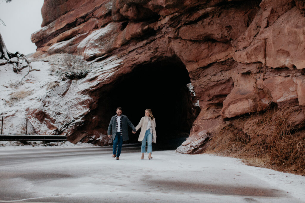 Couple holding hands walking through tunnel at Red Rocks, top Denver photoshoot locations