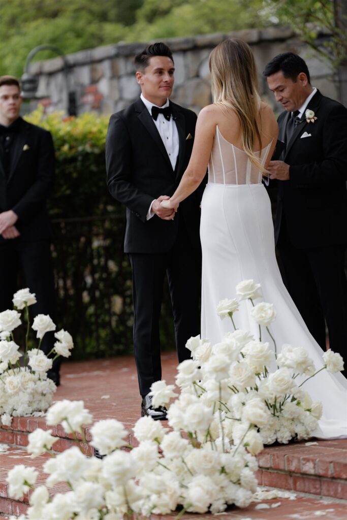 White roses surround bride and groom during courtyard wedding at Estate Yountville