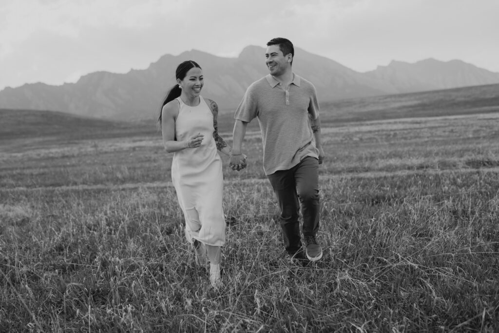 Couple running through field during Boulder flatirons engagement session
