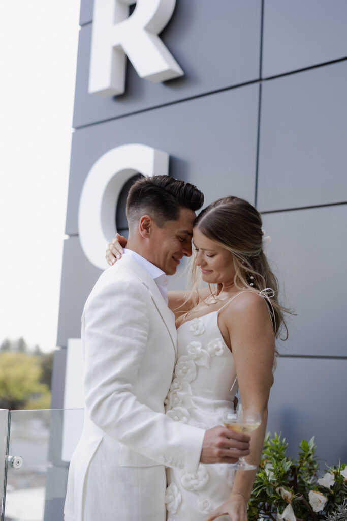 Bride and groom embrace during rooftop welcome event for Napa wedding