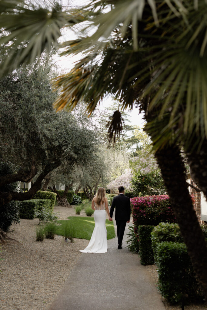 Bride and groom taking photos under palm trees during wedding photos at the Estate Yountville
