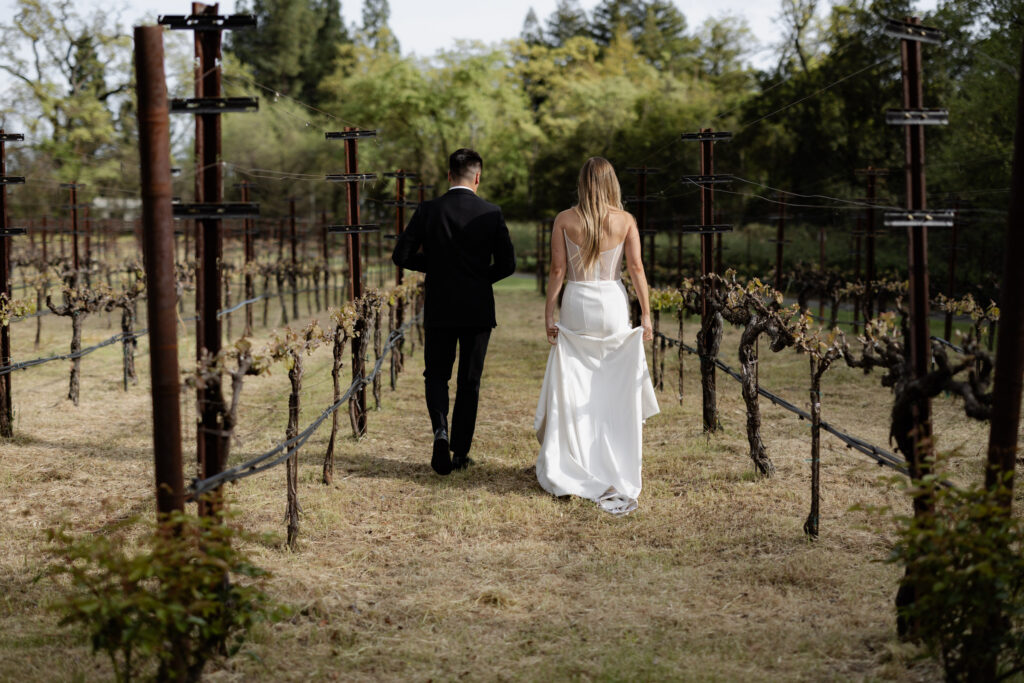 Sunset wedding photos of bride and groom walking in vineyard at the Estate Yountville