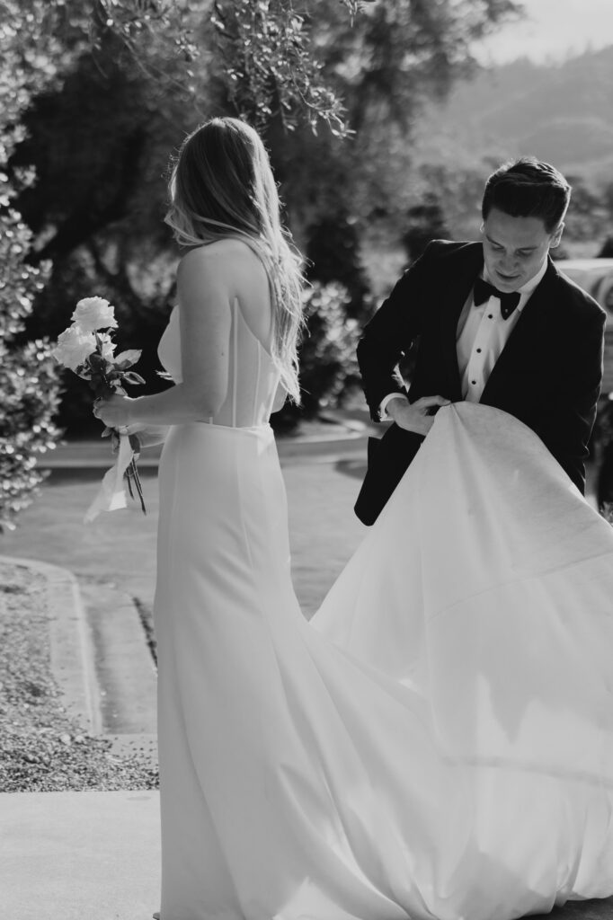 Groom holding brides dress during wedding photos at the Estate Yountville