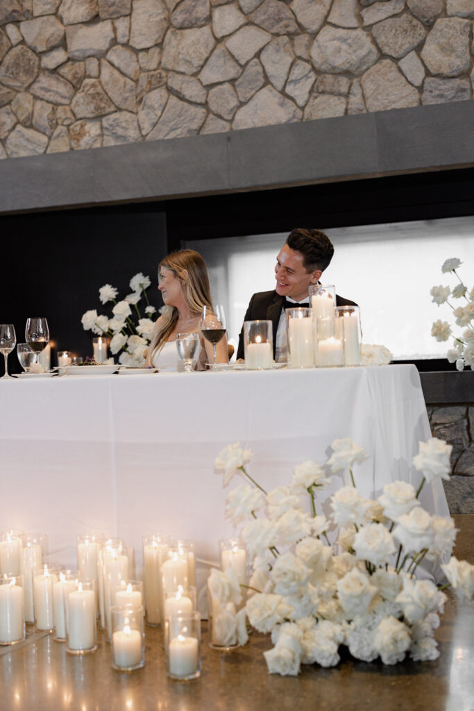 White candles and roses surround table of bride and groom at wedding at the Estate Yountville
