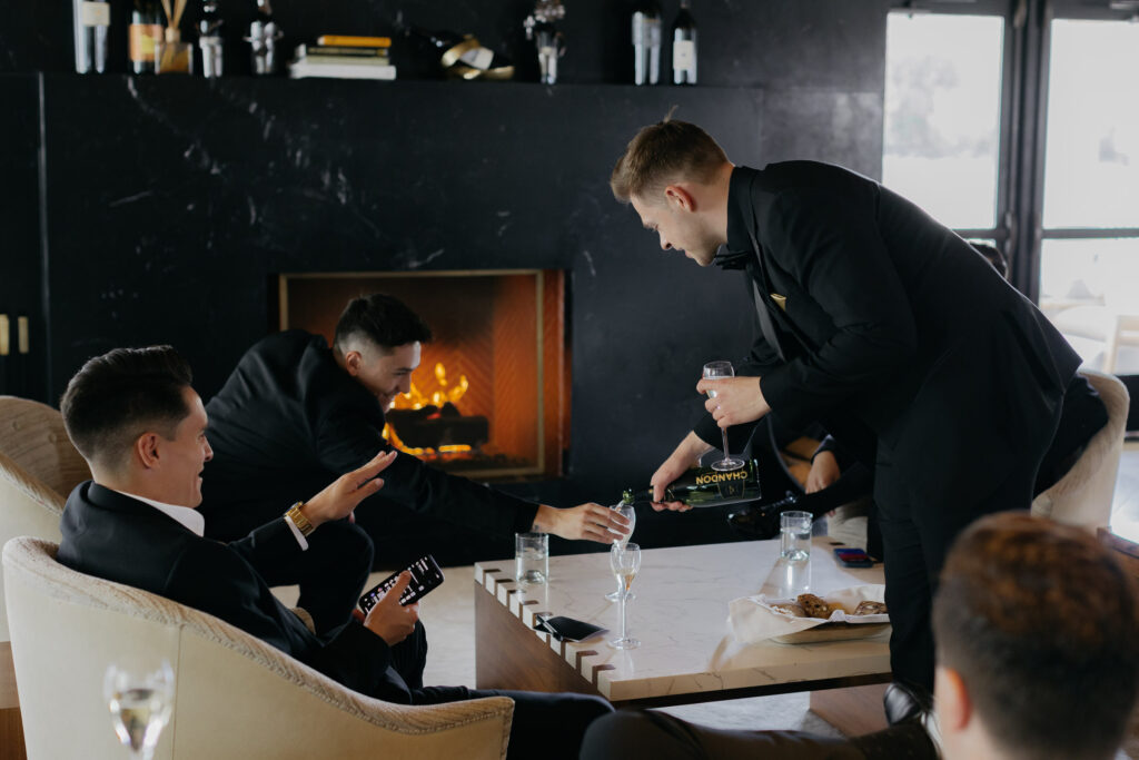 Groomsmen sit by fire inside the Hotel Villagio at the Estate Yountville