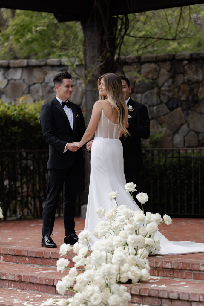 bride and groom surrounded by white roses during courtyard ceremony at the Estate Yountille