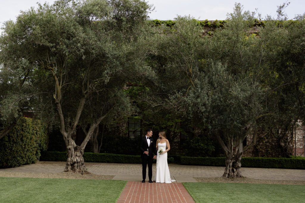 Bride and groom standing against greenery at the Estate Yountville during wedding photos