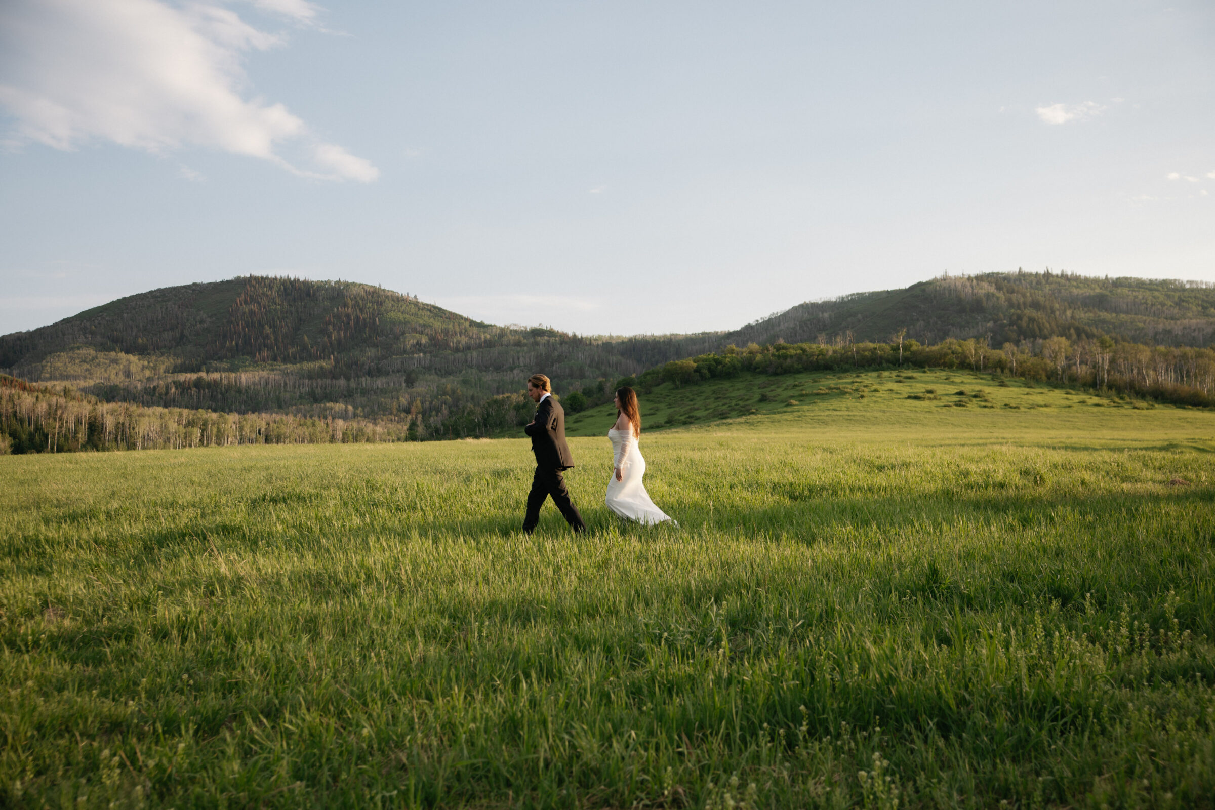 bride and groom walking in long grass during sunset photos at Flying Diamond ranch wedding