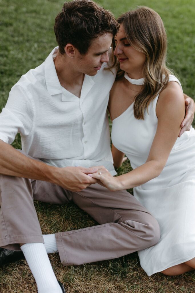 Couple sitting on grass of Cheesman park during engagement photo session