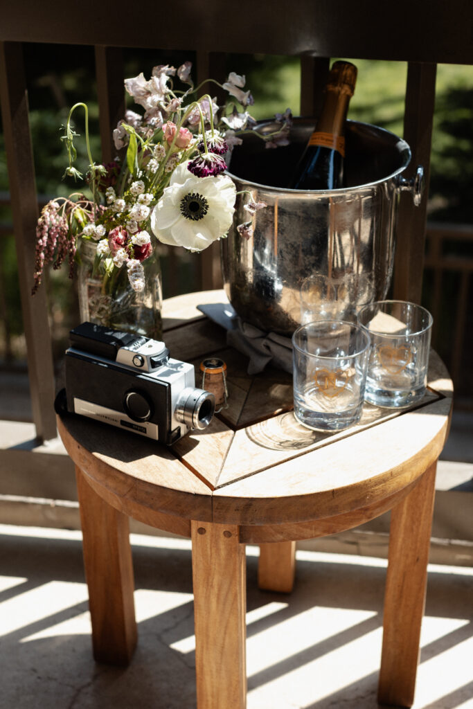 Champagne glasses and super 8 camera on table during Piney River Ranch elopement