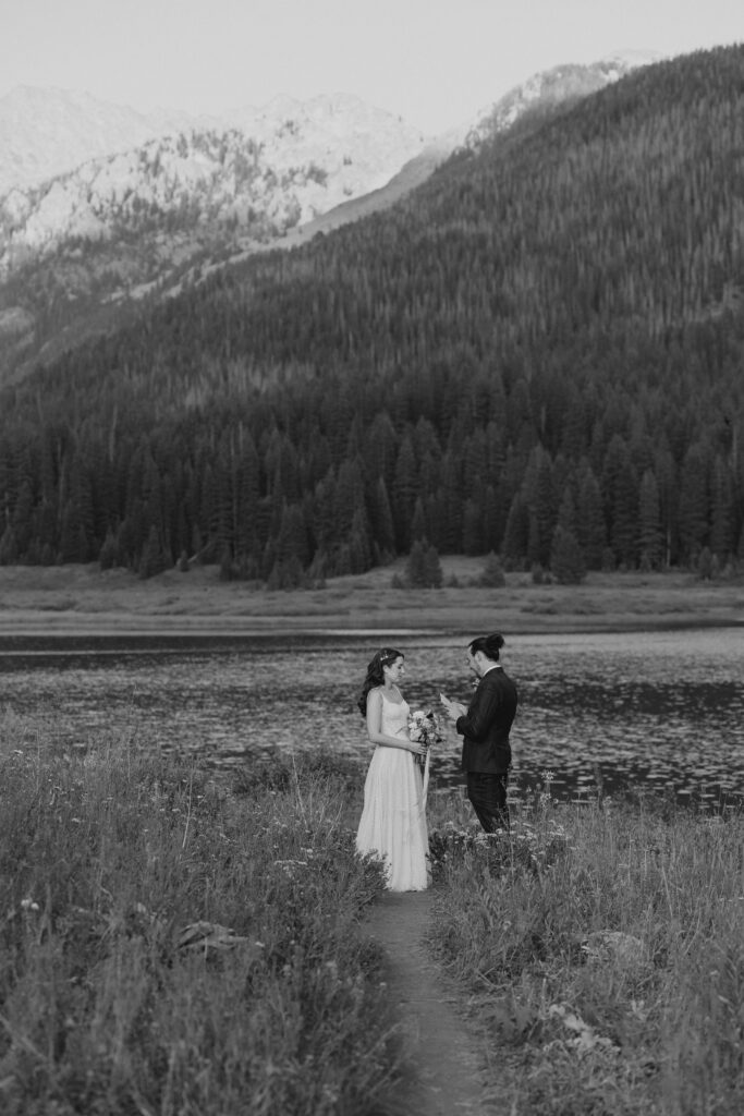 Couple saying vows in front of lake at Piney River Ranch