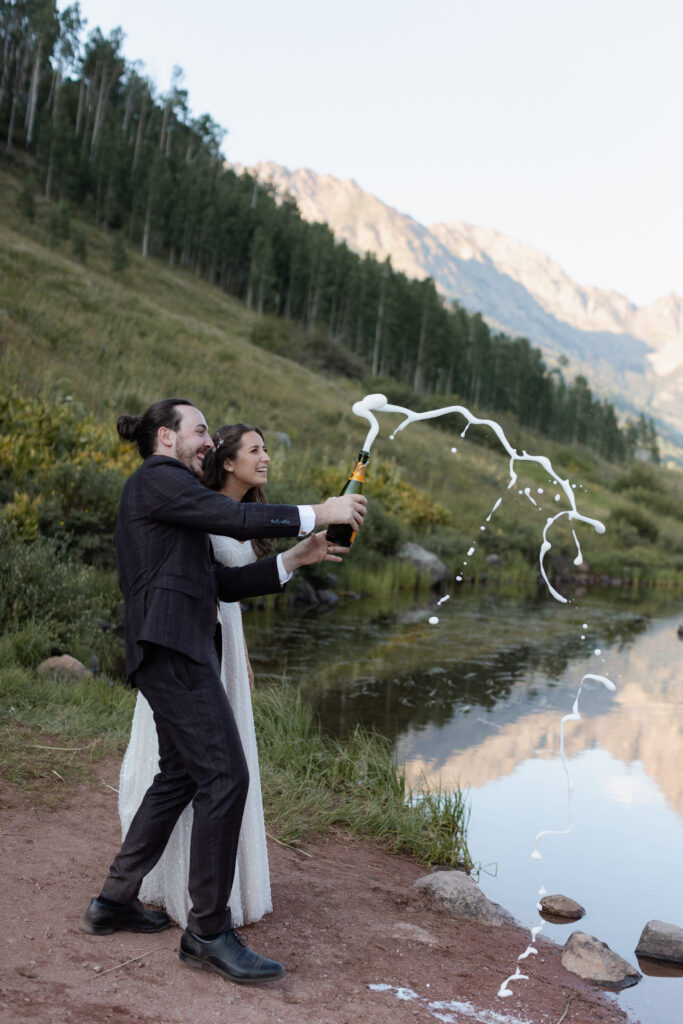 Couple pops champagne at Piney River Ranch elopement