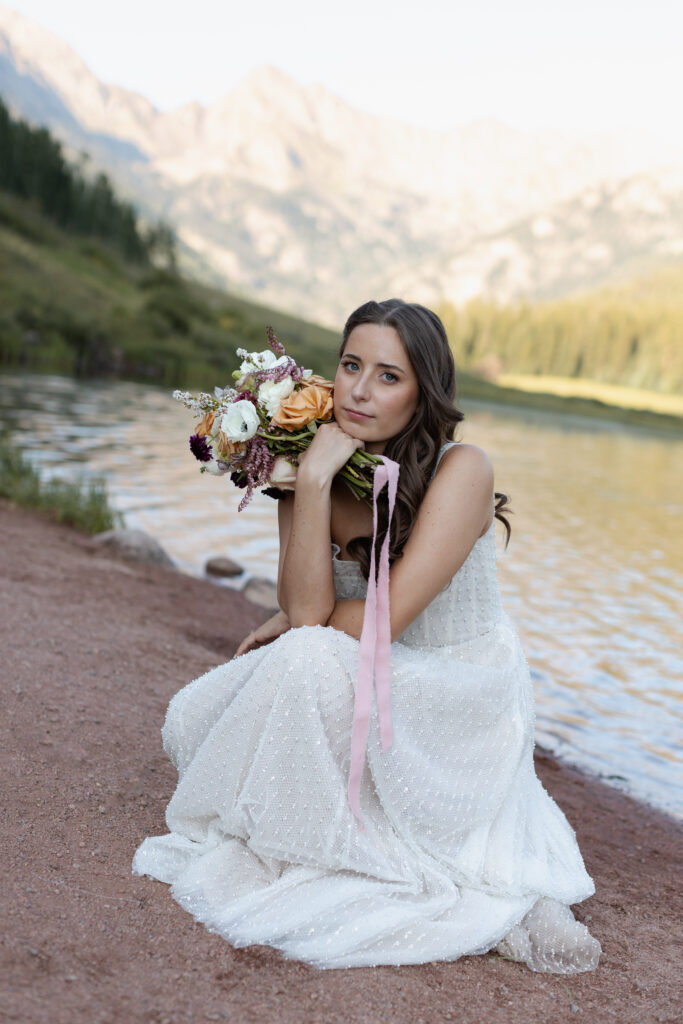 Bride sitting in front of lake at Piney River Ranch