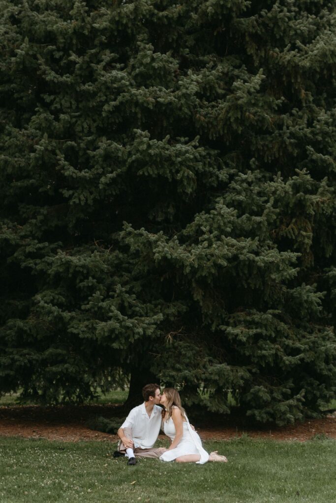 Couple kisses by tree during Cheesman park engagement photos