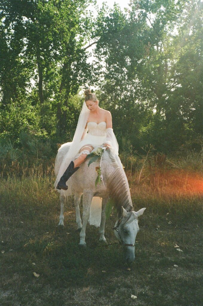 Bride sits on horse during wedding photos on 35mm film photography during Colorado wedding