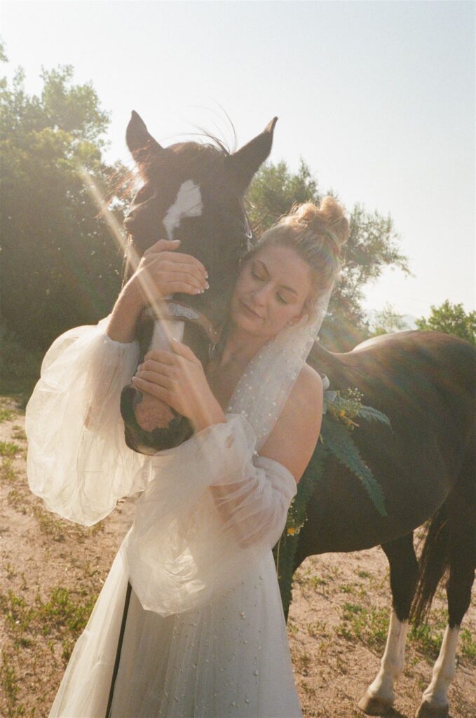 Bride posing with horse photographed on 35mm film at Colorado wedding