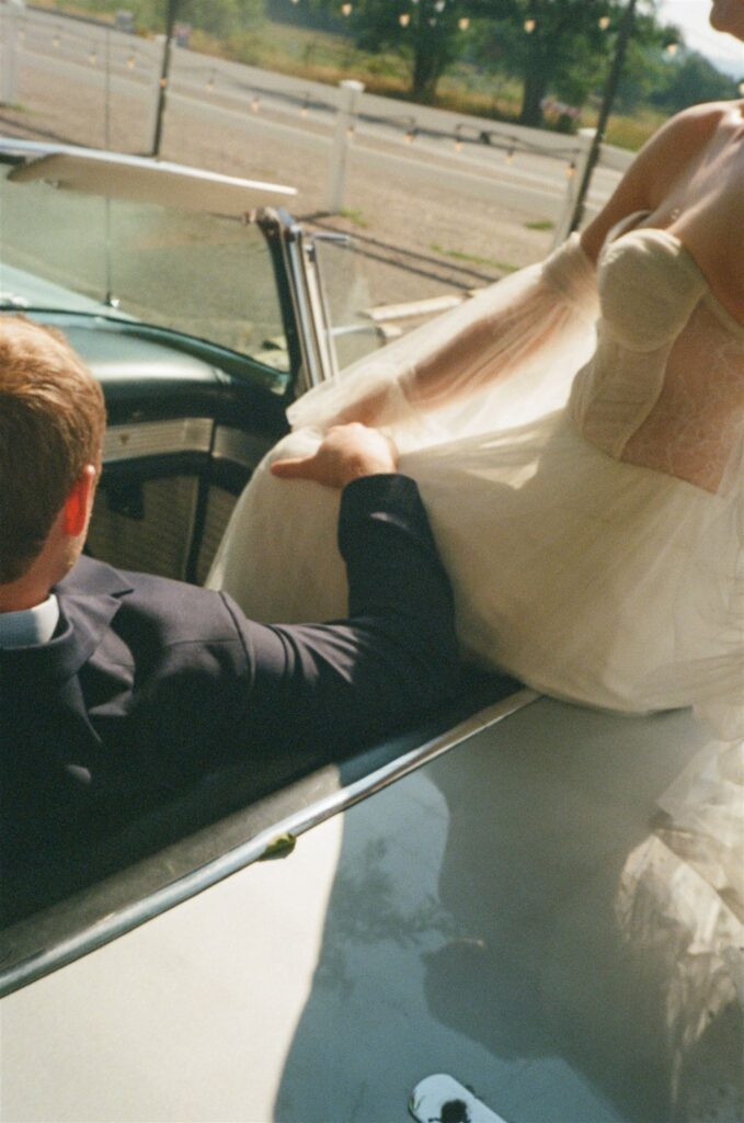 Couple sits in classic car during wedding photography on film portraits 