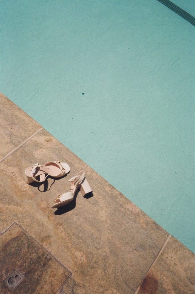 Wedding photography on film shows bride's shoes sitting by pool during Colorado wedding